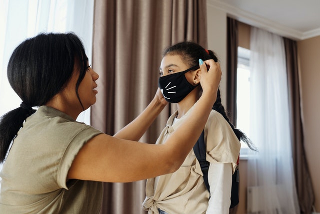 майка поставя на детето си предпазна маска за лице